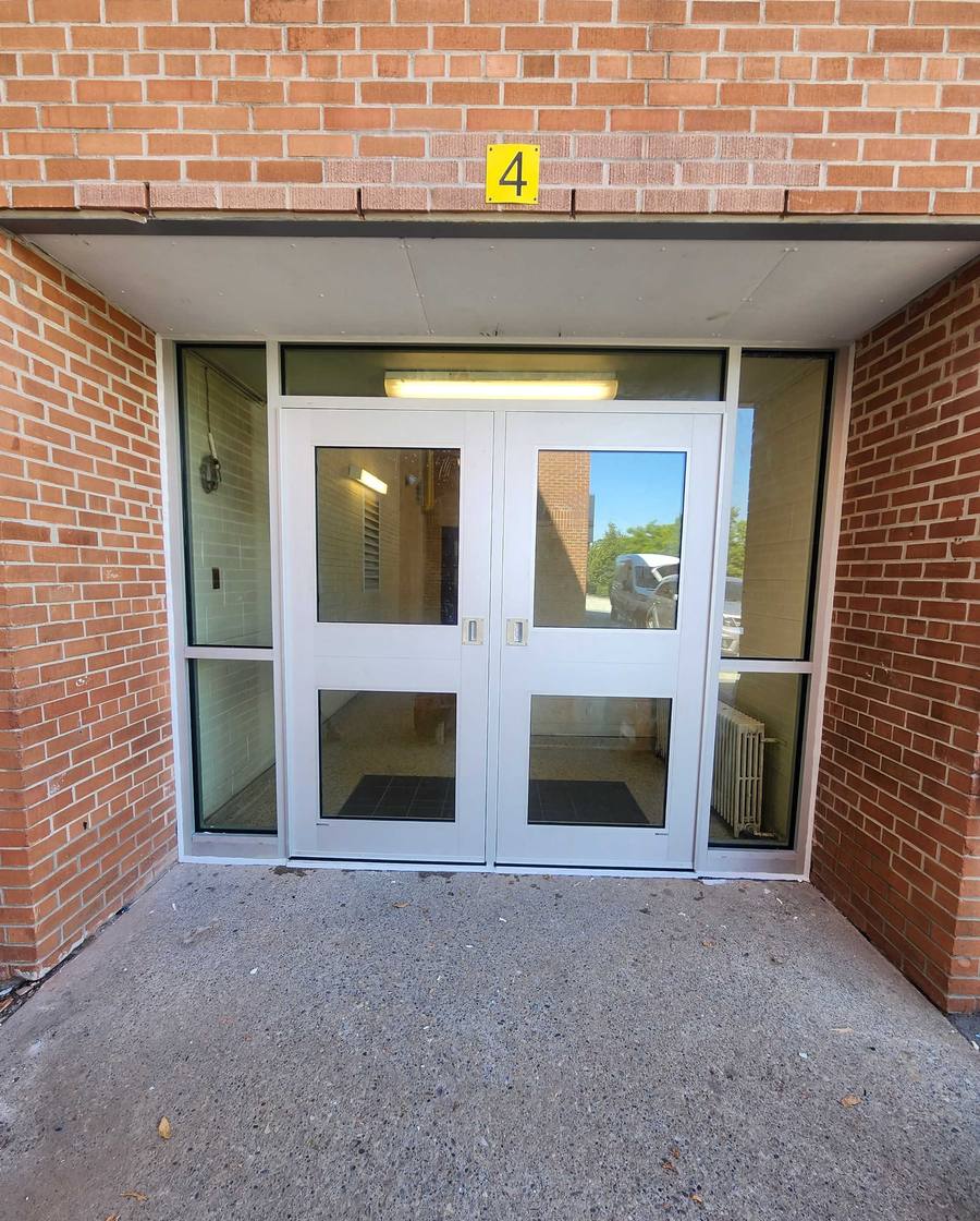 A clear-anodized aluminum double entrance with sidelites and a transom, set into a brick opening, installed by Canuck Door Systems