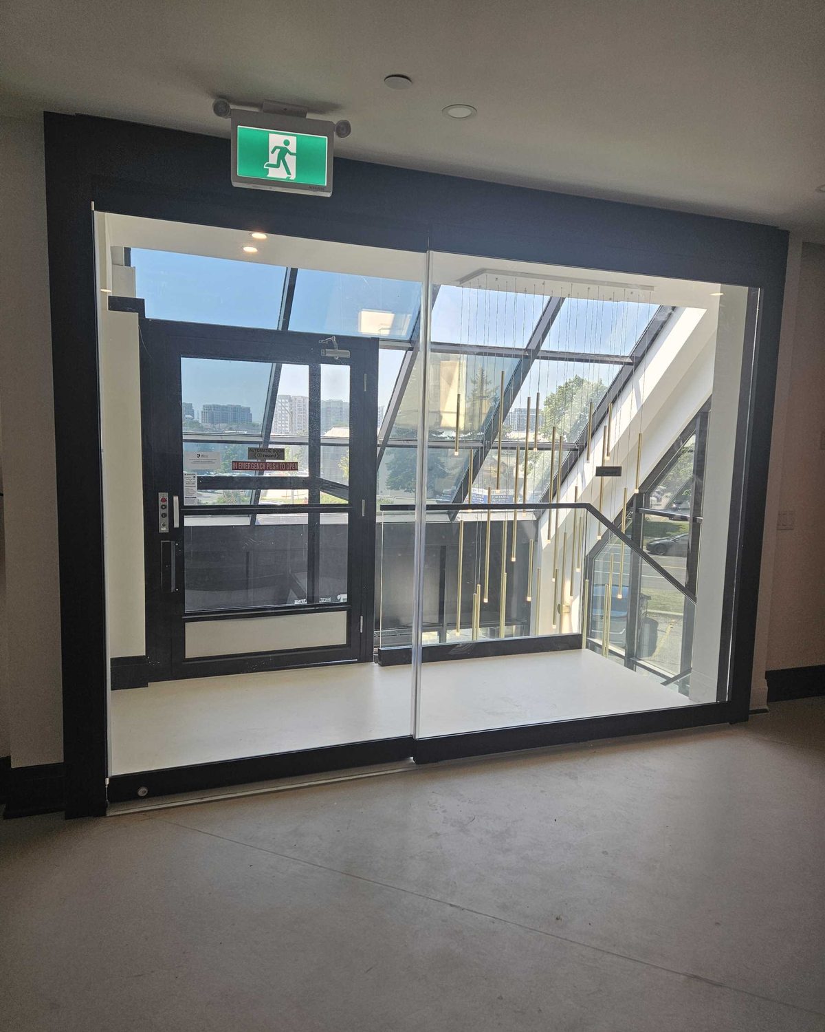 A dark-framed automatic sliding door entrance in the glazed vestibule of a medical clinic, installed by Canuck Door Systems