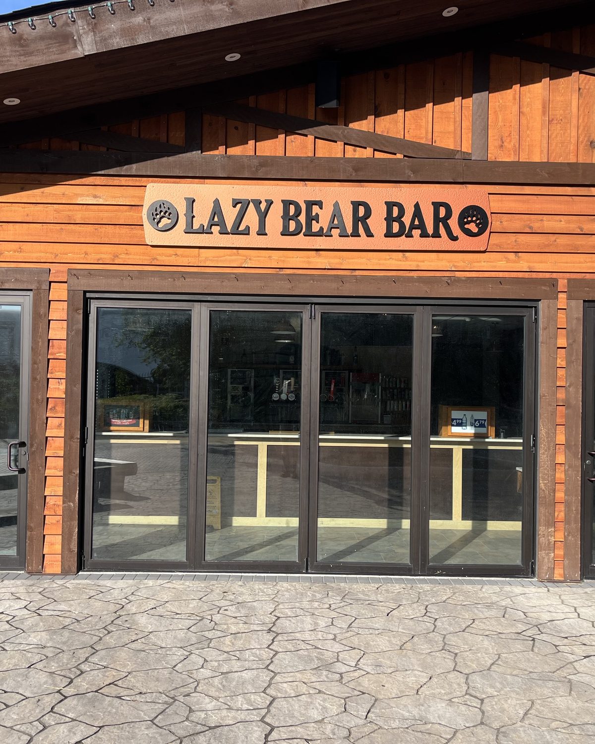 A run of dark-framed bi-folding glass doors closed across the frontage of the Lazy Bear Bar at Canada's Wonderland in Vaughan, installed by Canuck Door Systems
