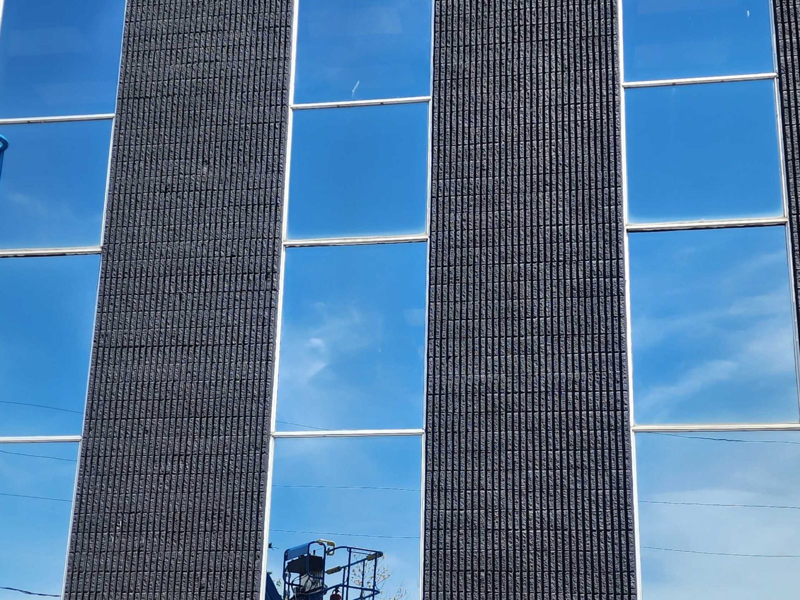 Floor-to-floor glazing running between the dark brick piers of a multi-storey commercial elevation, supplied and installed by Canuck Door Systems