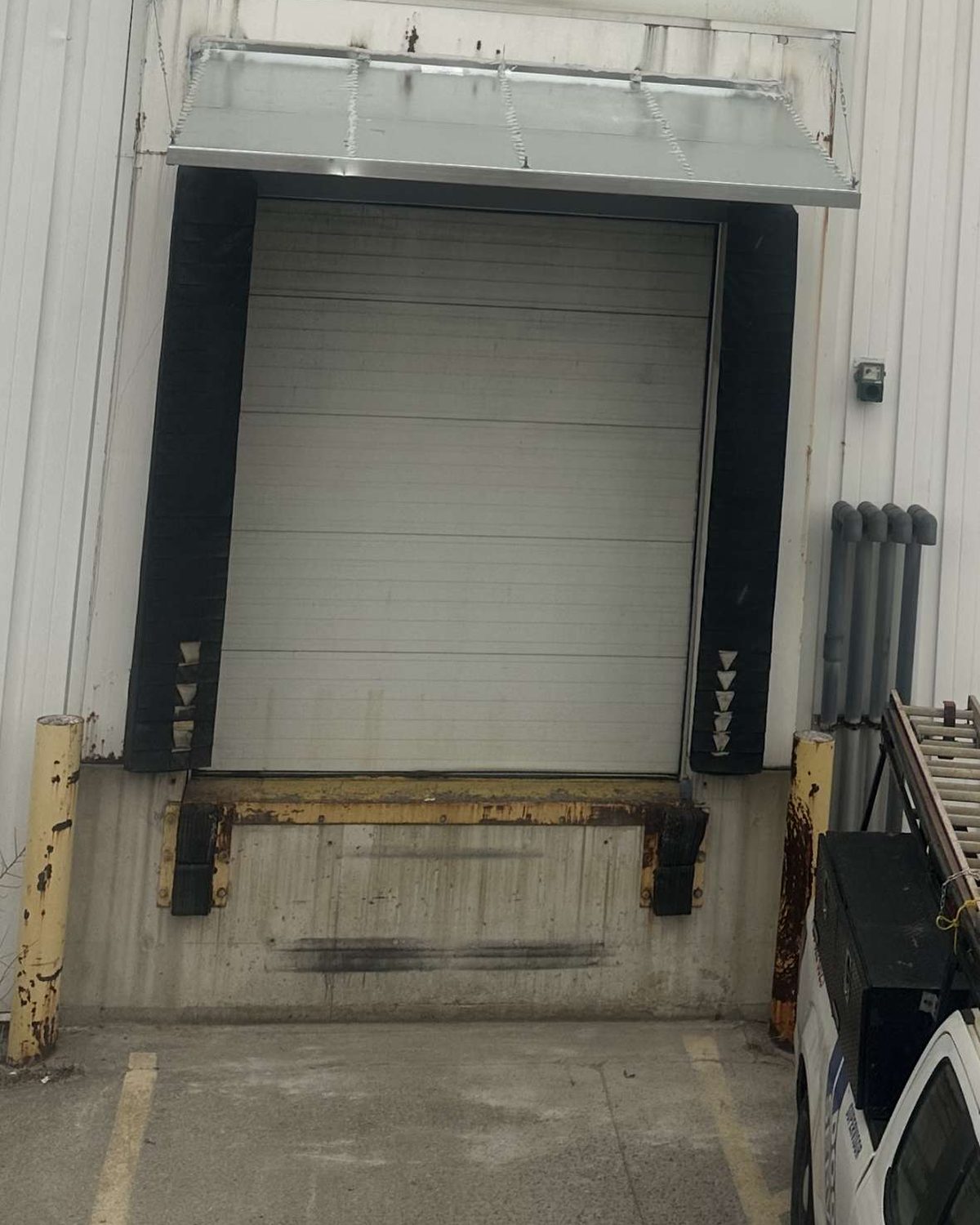 An older dock leveler frame showing corrosion below a black compression dock seal, photographed on a service visit by Canuck Door Systems