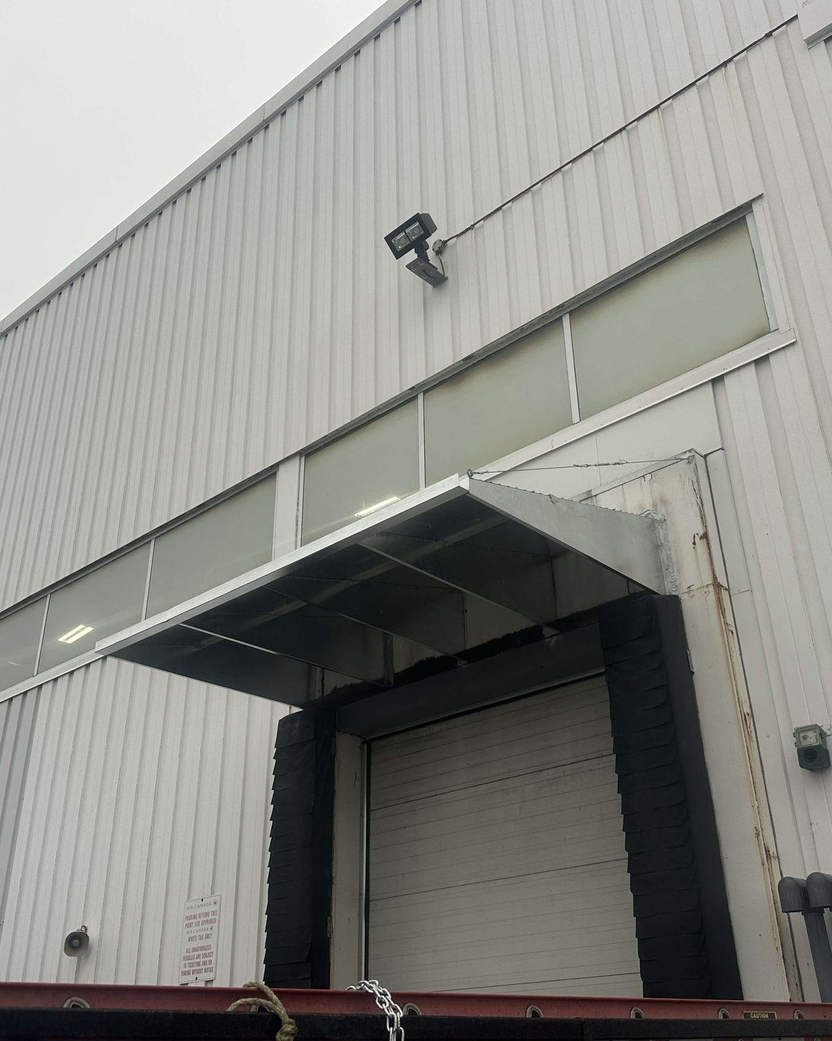 A galvanized head canopy above black compression dock seal pads at a loading dock position, photographed by Canuck Door Systems