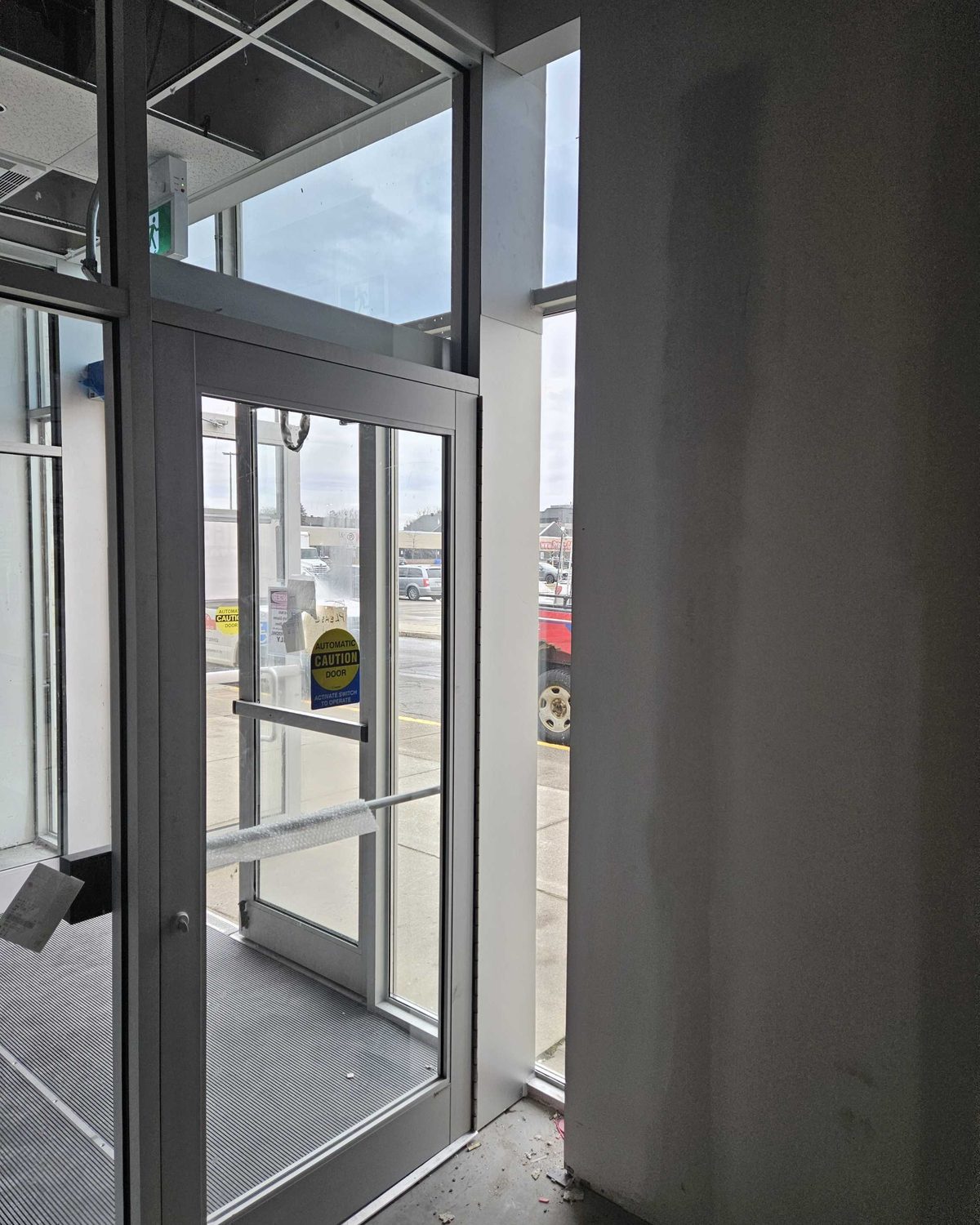 A new aluminum-framed glazed entrance door and screen installed in a commercial fit-out, by Canuck Door Systems