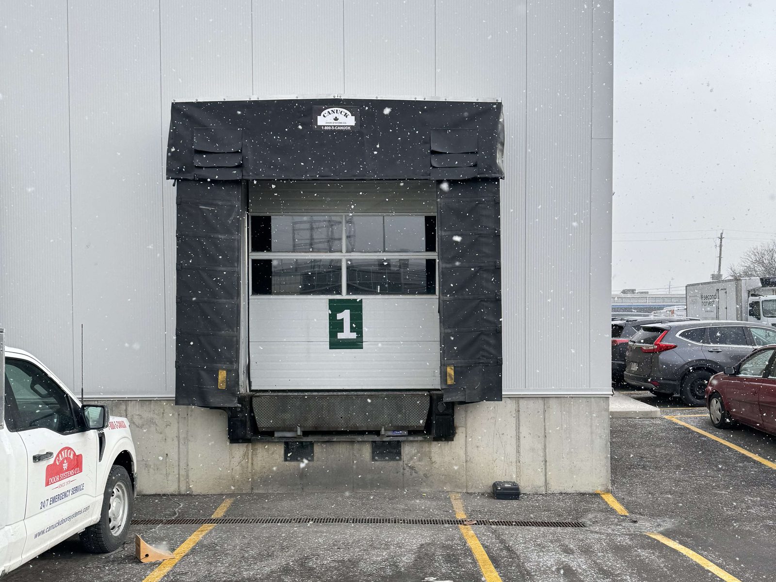 A numbered loading dock position with a fabric dock shelter, leveler and overhead door at a commercial building, maintained by Canuck Door Systems