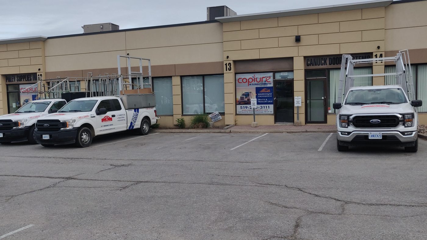 Canuck Door Systems service trucks with glass racks parked outside the company's unit at 1645 Bonhill Road in Mississauga