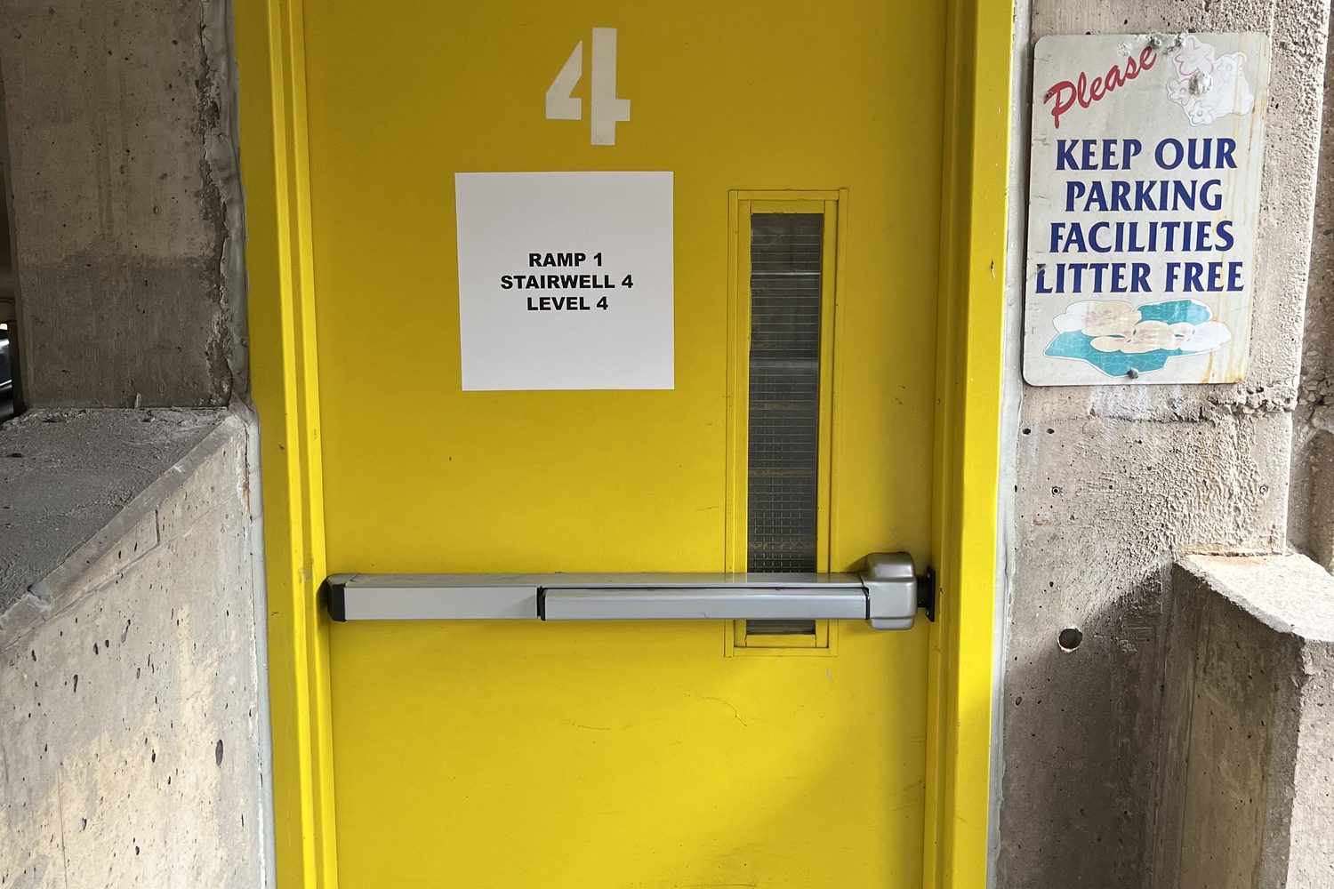 A numbered stairwell fire door with an exit device and posted signage in a parking structure, inspected by Canuck Door Systems