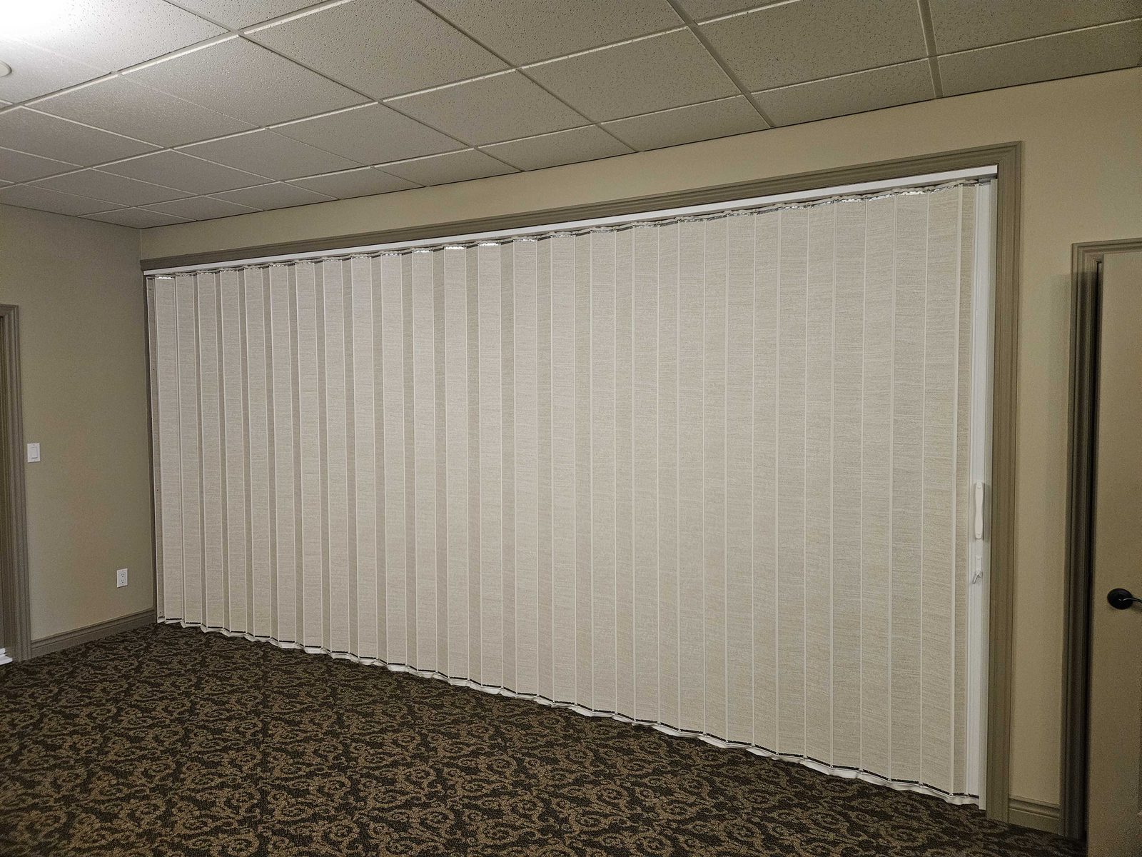 A cream vinyl-faced accordion folding partition closed across a carpeted function room, installed by Canuck Door Systems