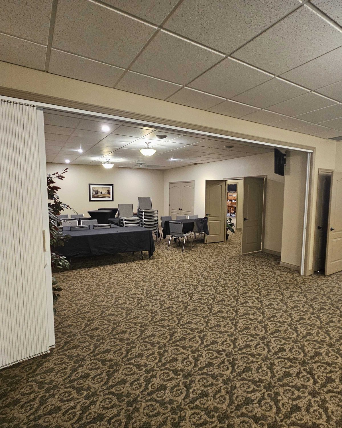 An accordion folding partition stacked open against a jamb, with the adjoining function room visible through the opening, installed by Canuck Door Systems