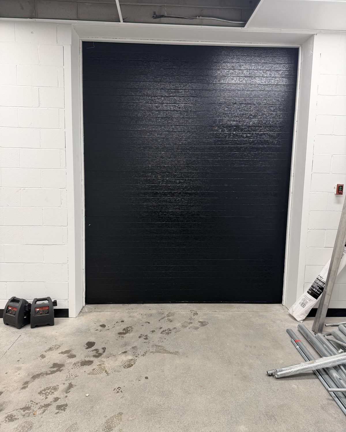 A commercial overhead garage door in an industrial building elevation, installed by Canuck Door Systems