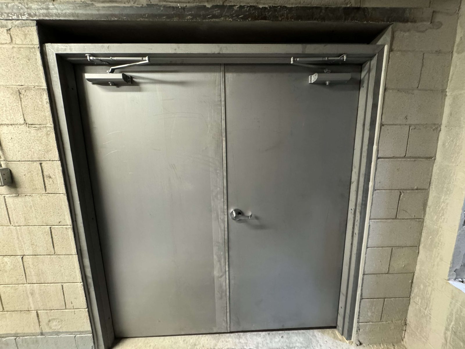 A pair of hollow metal doors in a welded steel frame with surface-mounted closers, installed by Canuck Door Systems
