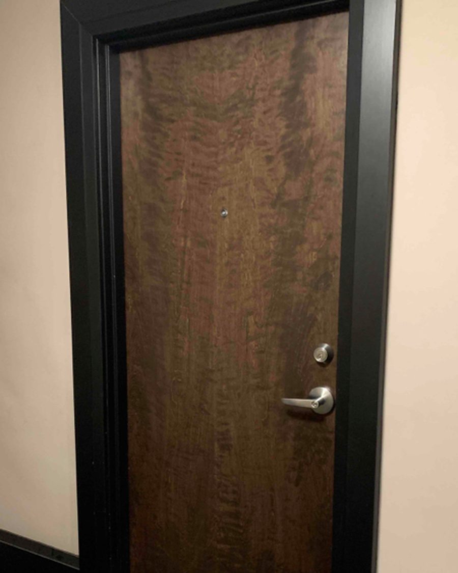 A dark-stained veneer door with lever and cylinder hardware, hung in a painted steel frame, installed by Canuck Door Systems