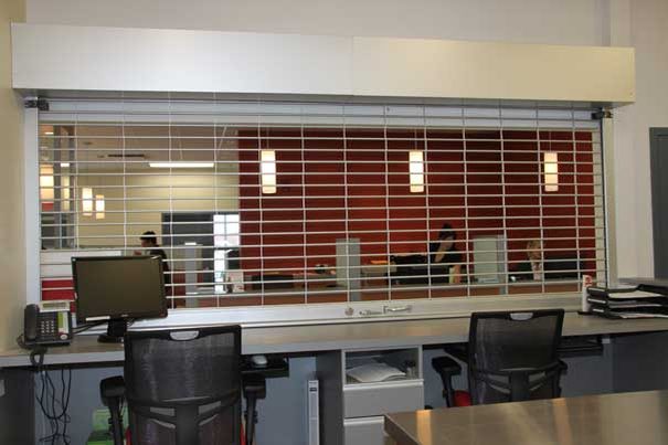 An open-style rolling grille closed across an interior service counter in an office, installed by Canuck Door Systems