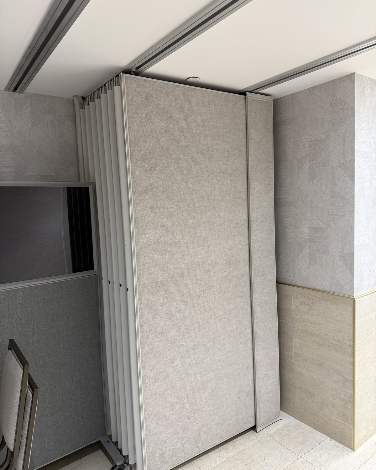 Fabric-faced operable partition panels stacked flat against each other at the end of a room, installed by Canuck Door Systems