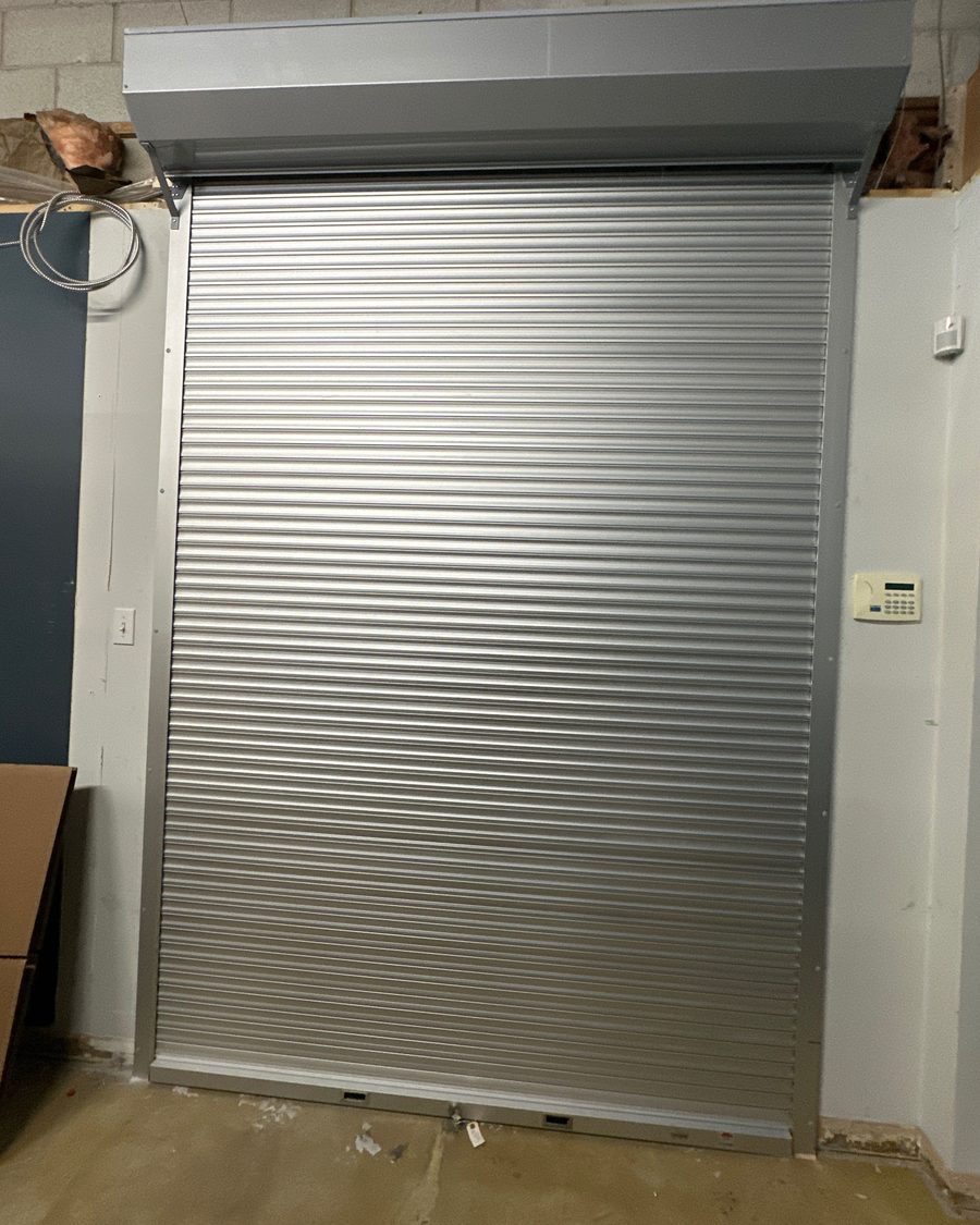 A commercial overhead door closed across an industrial bay opening at ARJ Airparts, installed by Canuck Door Systems