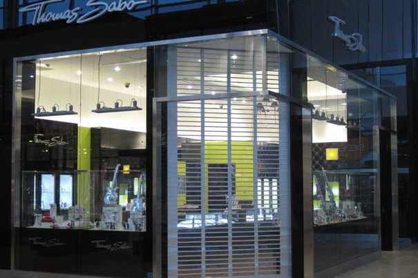 A polycarbonate rolling grille closed across the glazed elevations of a jewellery kiosk in a shopping centre, installed by Canuck Door Systems