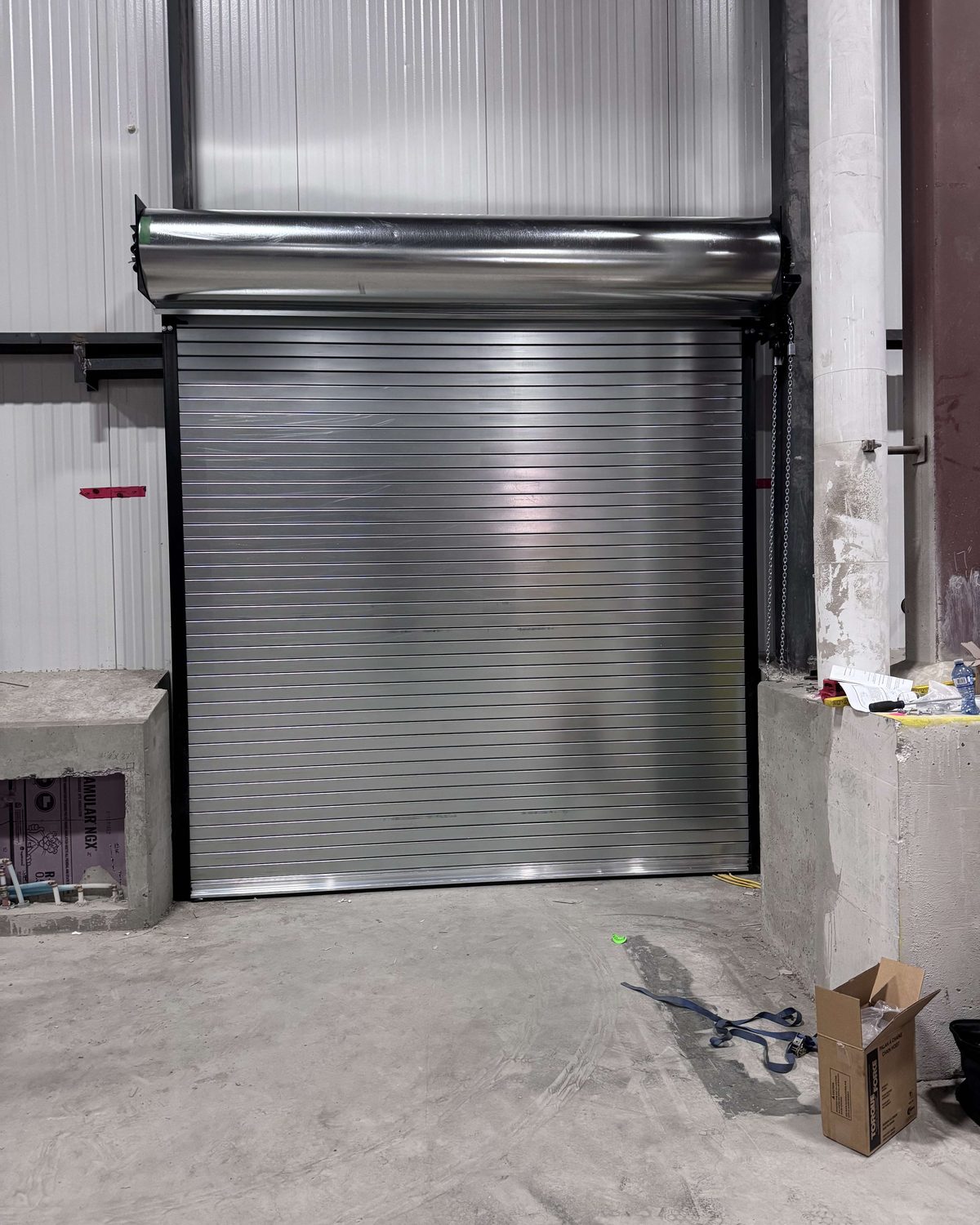 A rolling steel door curtain at an industrial bay opening, installed by Canuck Door Systems