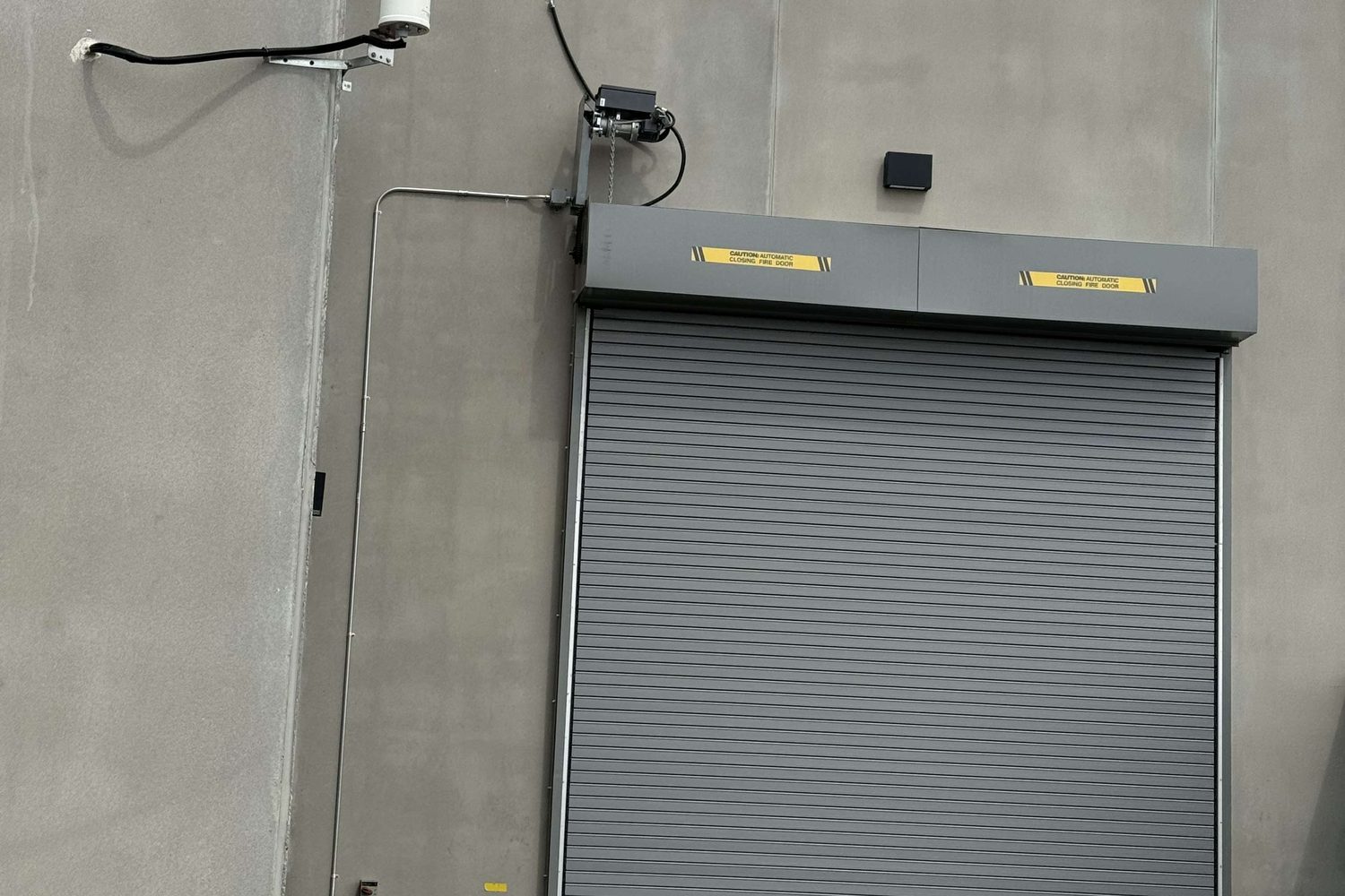 A rolling steel door in a plant opening with the coil and brackets visible above, installed by Canuck Door Systems
