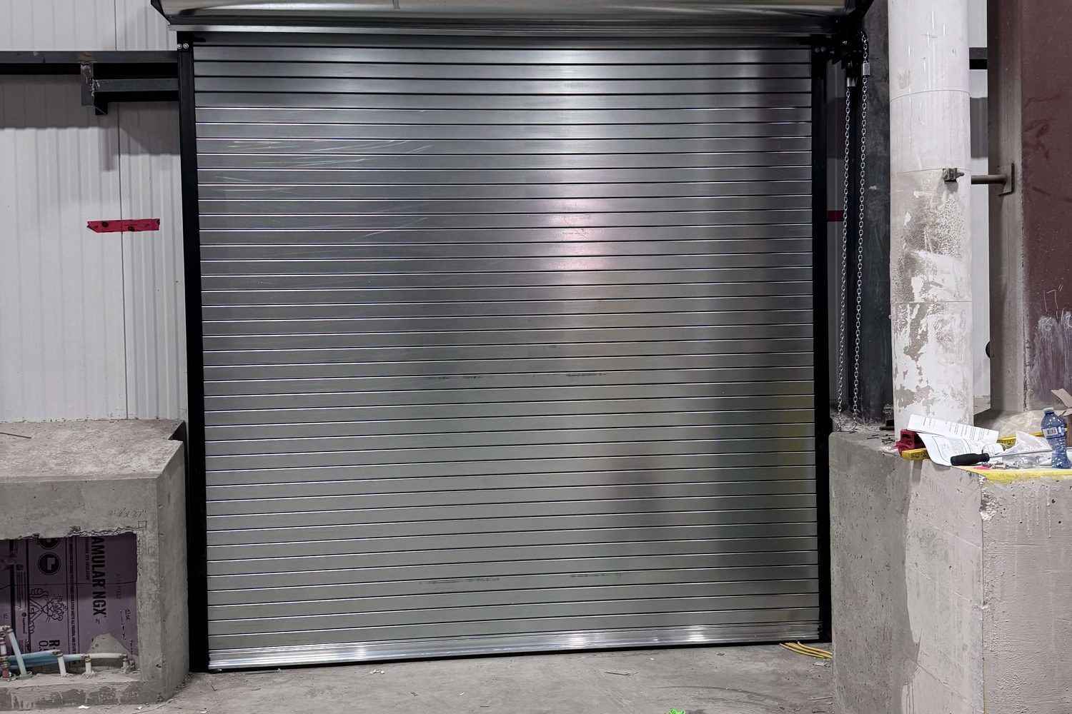 A rolling steel shutter curtain closed in its guides inside an industrial building, installed by Canuck Door Systems