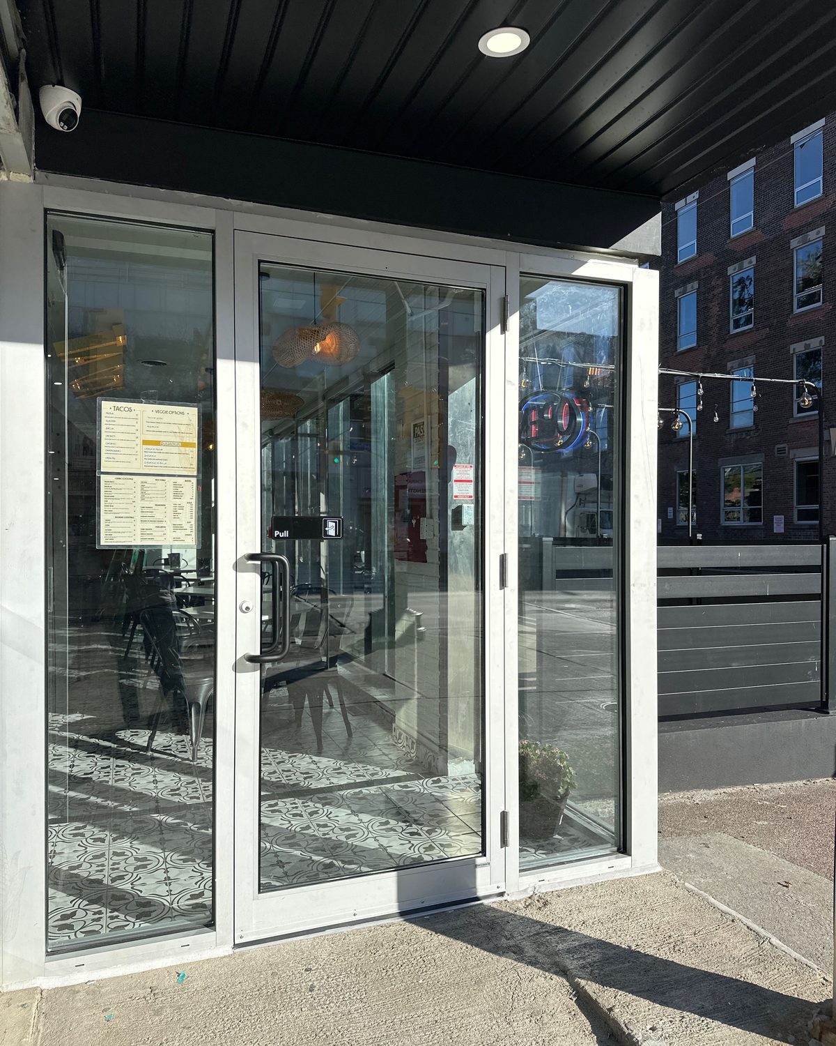 A replaced clear-anodized aluminum entrance door and glazed sidelites under a restaurant canopy, installed by Canuck Door Systems