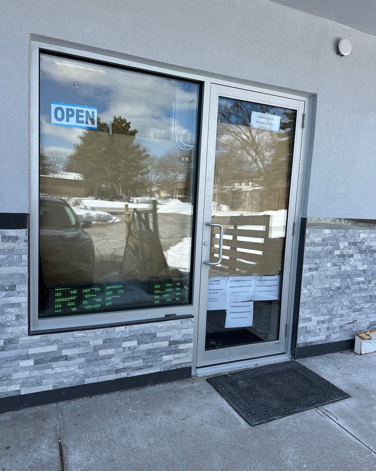 An aluminum storefront entrance door with an entrance mat and threshold, of the type Canuck Door Systems fits with pile weatherstrip and sweeps