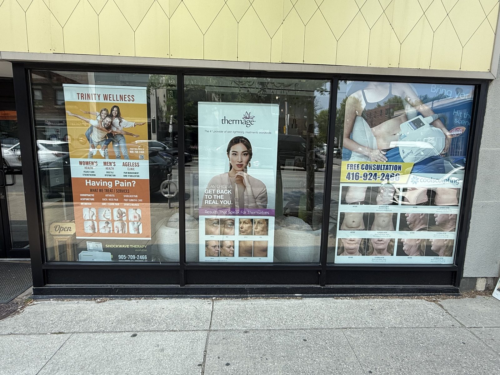 A retail storefront glazed in three large bays of dark aluminum framing at street level, carrying the tenant's window graphics, glazed by Canuck Door Systems