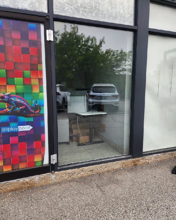 A storefront display bay in dark aluminum framing with window graphics, glazed by Canuck Door Systems