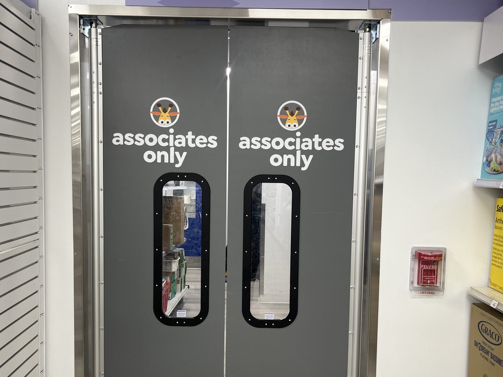 A pair of double-acting impact traffic doors on a retail stockroom opening, with vision windows, stainless jamb guards and kick plates, installed by Canuck Door Systems
