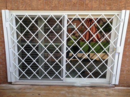 White expandable security gate locked across a sliding patio door
