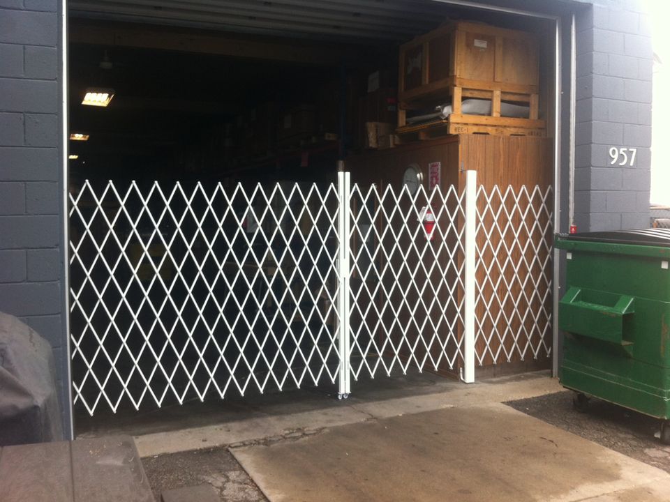 White expandable steel gate pulled across an open warehouse door