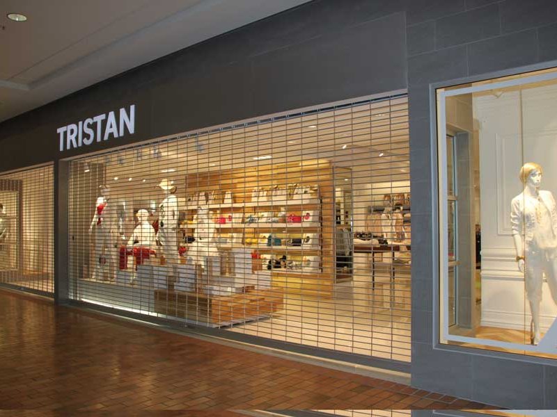 Rolling security grille lowered across the front of a clothing store in a mall