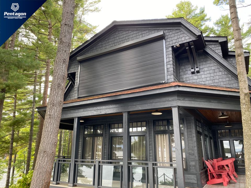 Rolling shutters over the windows of a lakeside cottage among pine trees