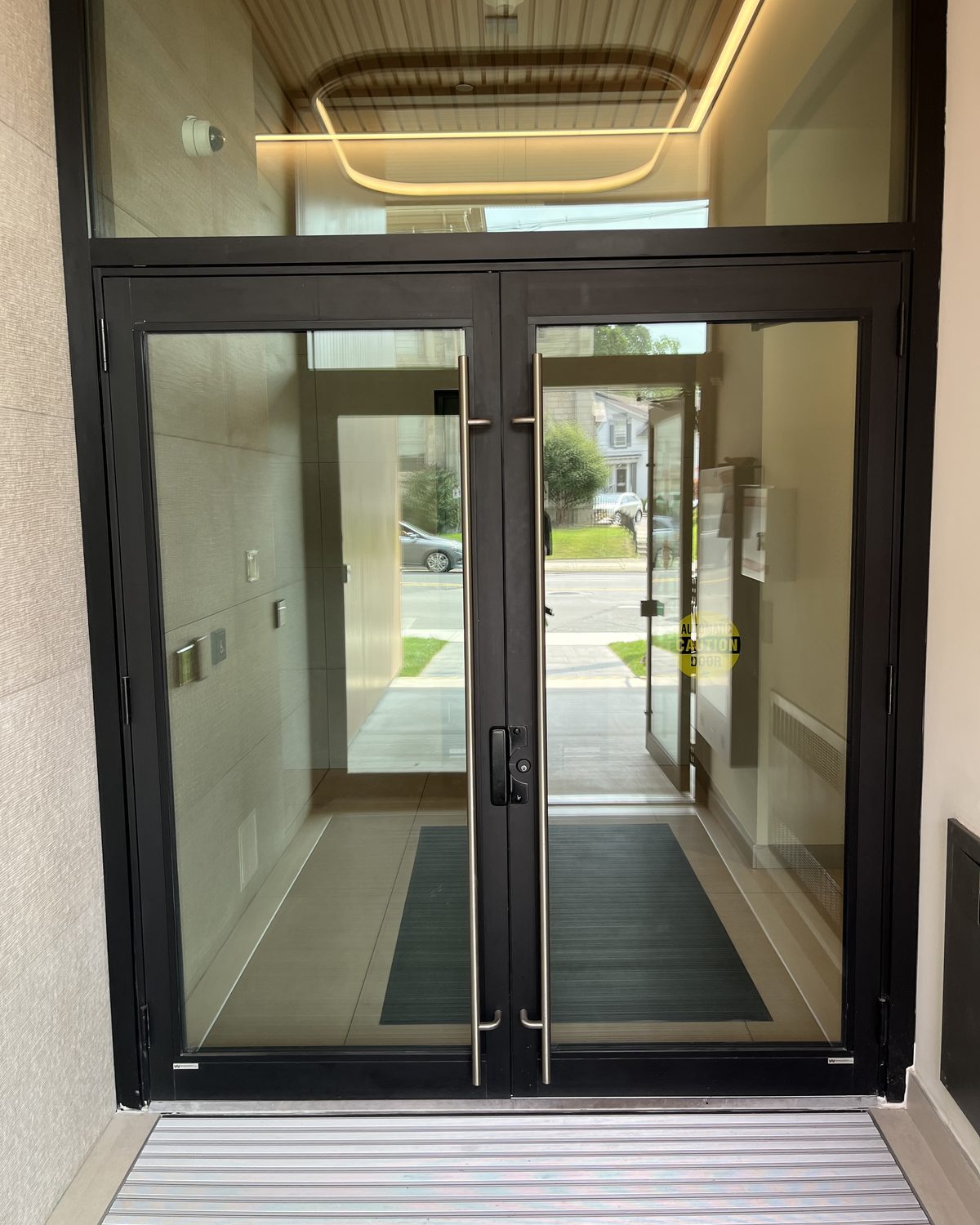 A pair of dark-framed glass entrance doors under a tall glazed transom, seen from inside the lobby of Centurion's building in Dundas