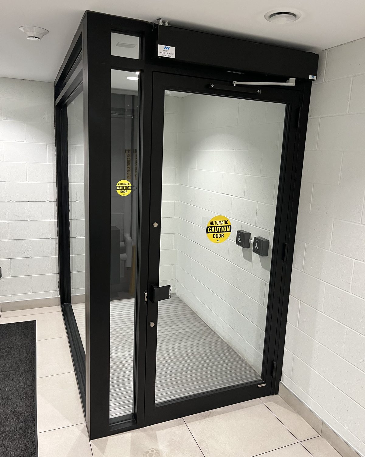A dark-framed glass vestibule enclosure with a door, inside Centurion's building in Dundas