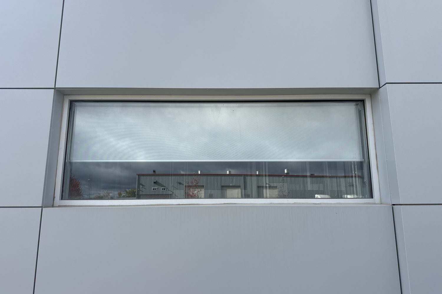 A long horizontal aluminum-framed window set into the grey metal panel wall at 30 Todd Road, Georgetown