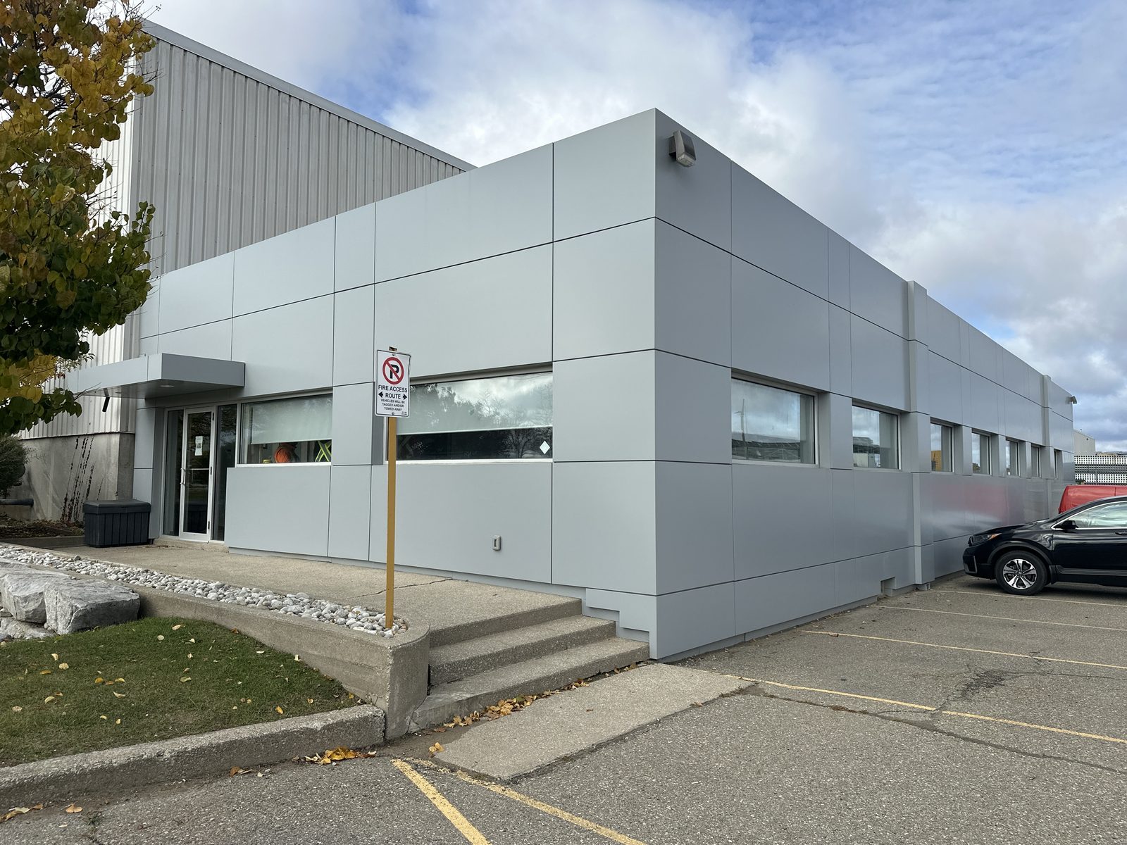 The single-storey grey-panelled building at 30 Todd Road in Georgetown, with a row of new aluminum windows along the wall and an entrance under a small canopy, replaced by Canuck Door Systems