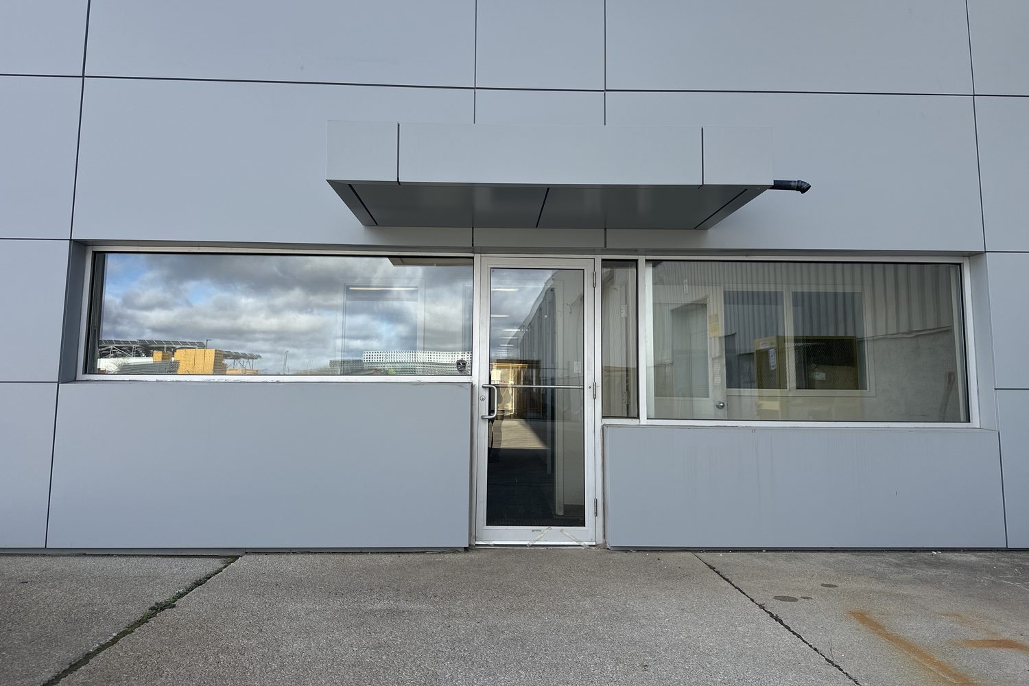 A glazed entrance door between two wide aluminum windows under a small canopy on the grey-panelled front at 30 Todd Road, Georgetown