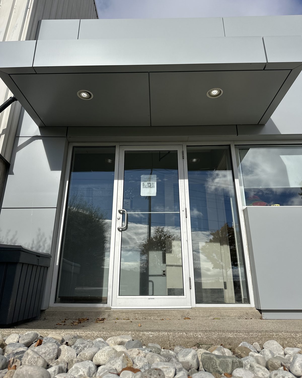 A glazed aluminum storefront entrance under a lit canopy on the grey-panelled building at 30 Todd Road, Georgetown