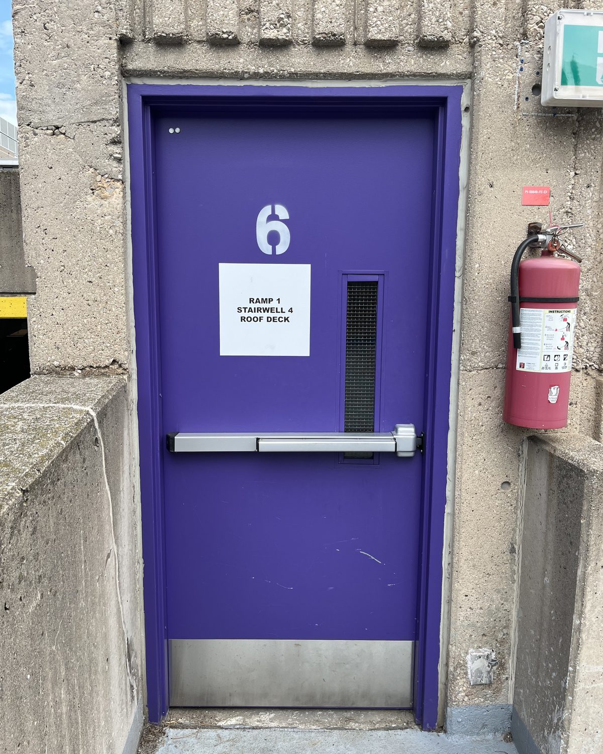 A purple hollow metal stairwell door with a panic bar and a large number 6, set in a concrete wall of the St. Joseph's Healthcare Hamilton parking garage