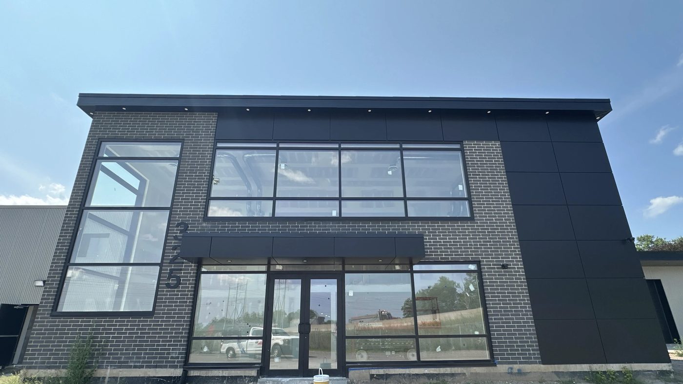 The front elevation of the new Hamilton office block — a band of black-framed aluminum windows across the second floor above a glazed aluminum storefront entrance and sidelites at grade
