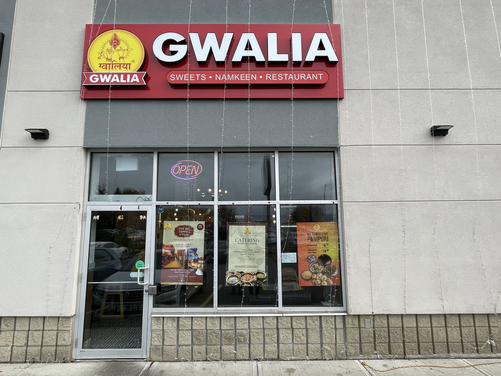 A new aluminum storefront with a glazed entrance door and a row of windows below a restaurant sign, one of the units at the plaza at 1379 Upper James Street in Hamilton, installed by Canuck Door Systems