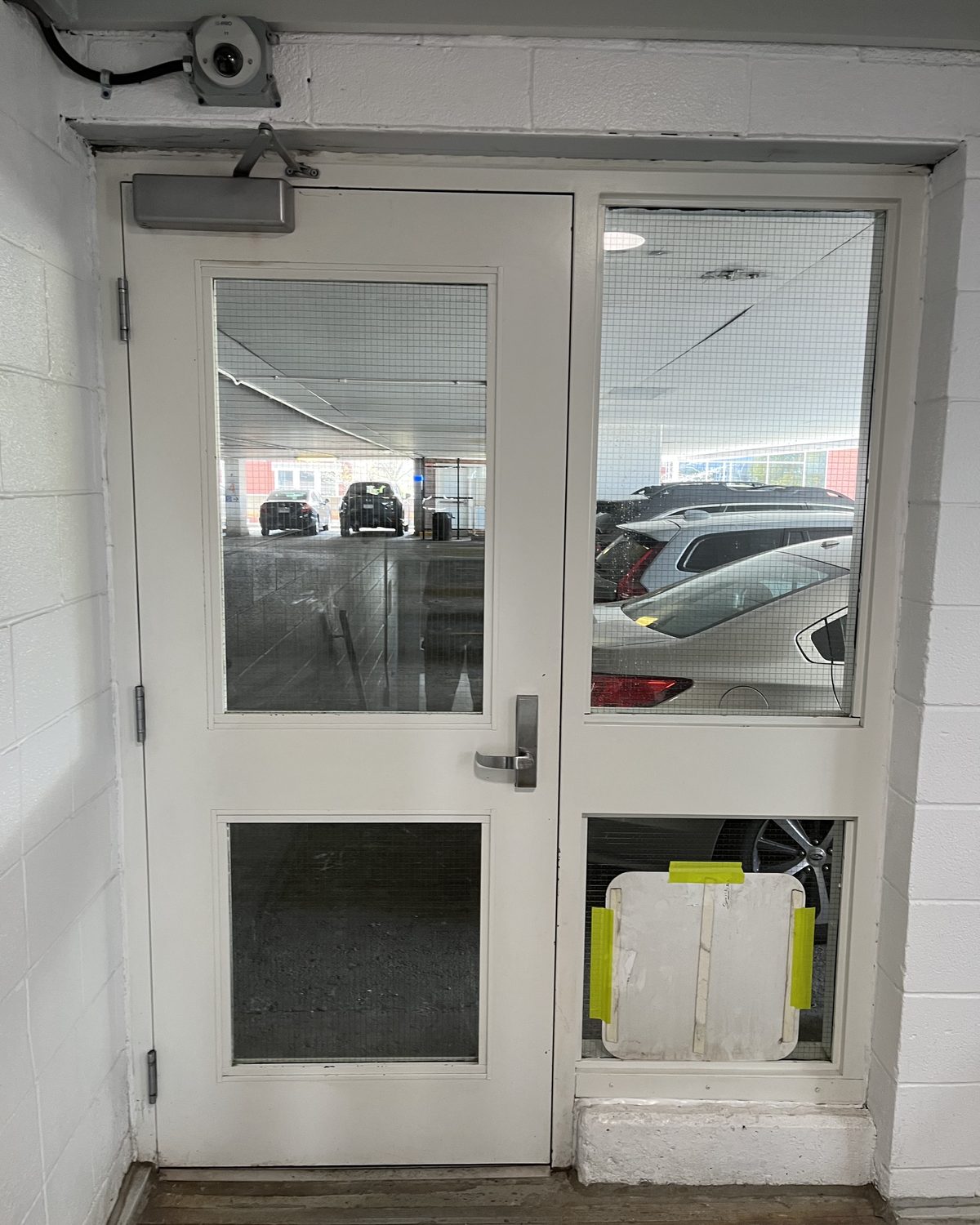 A white hollow metal door with a glazed sidelite opening onto a parking deck at the Grand River Hospital garage in Kitchener