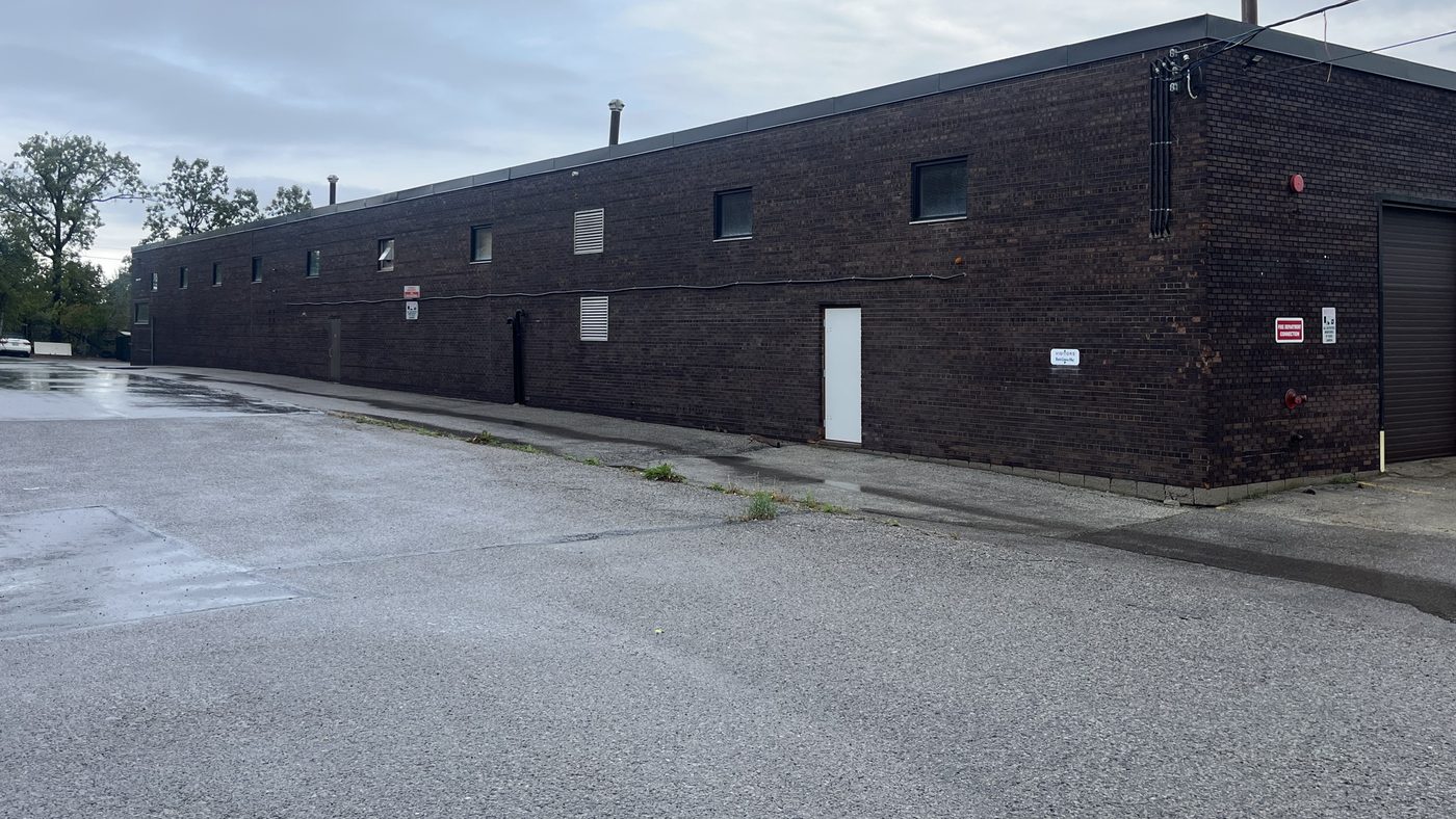 The long, low dark brick building of Sable Metal Fabrication in Markham, with small windows along the wall and a paved yard in front