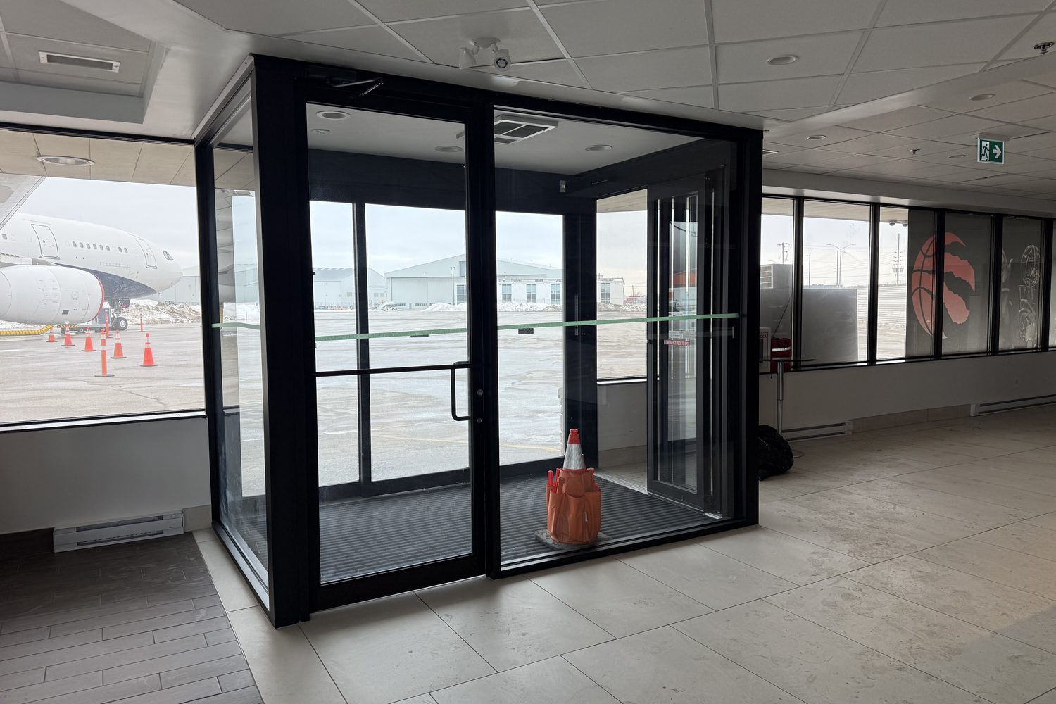 Inside the new glass and aluminum vestibule at Signature Aviation in Mississauga, with an aircraft visible through the glass beyond the doors