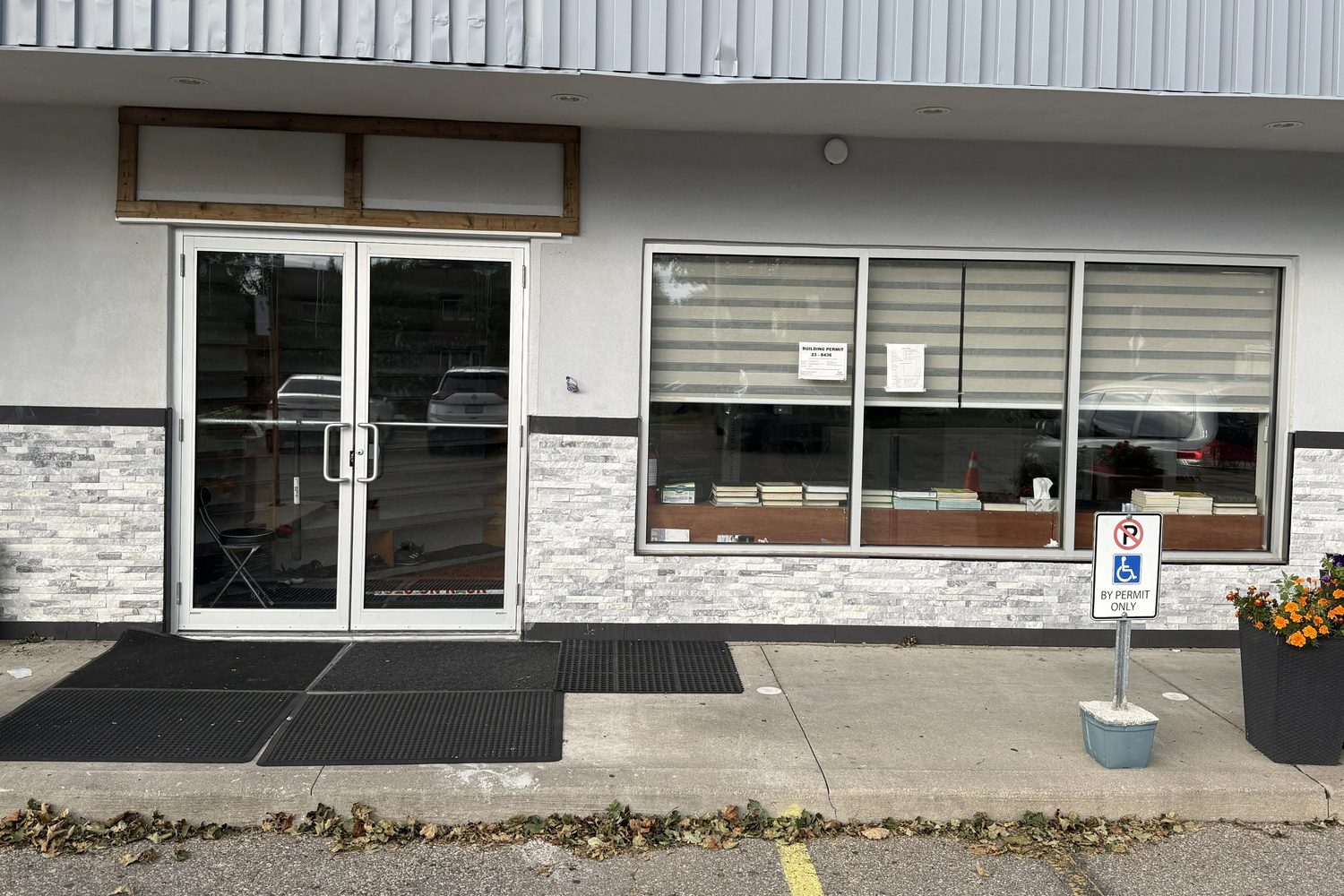 A replaced unit at the Mississauga plaza: a pair of clear anodized HERD 218 series aluminum doors beside a three-lite fixed storefront window over a stone veneer base