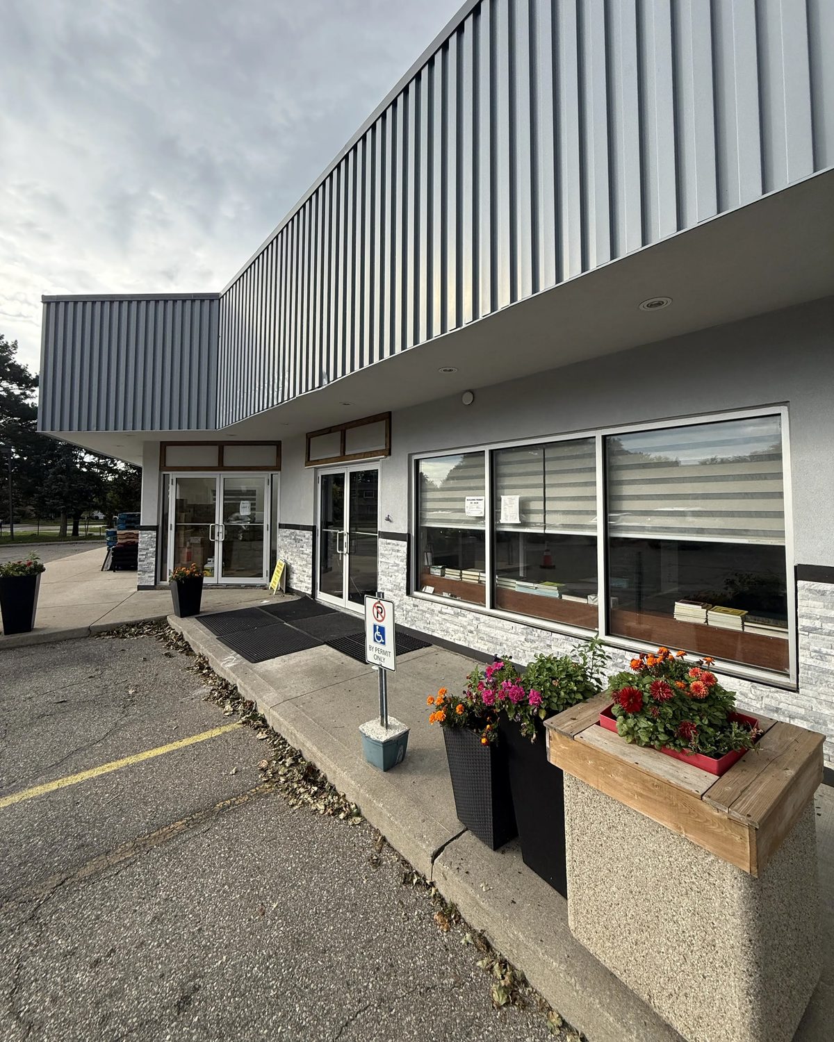 Looking along the Mississauga plaza's walkway at a run of new aluminum storefront windows and doors set into white stucco and stone veneer