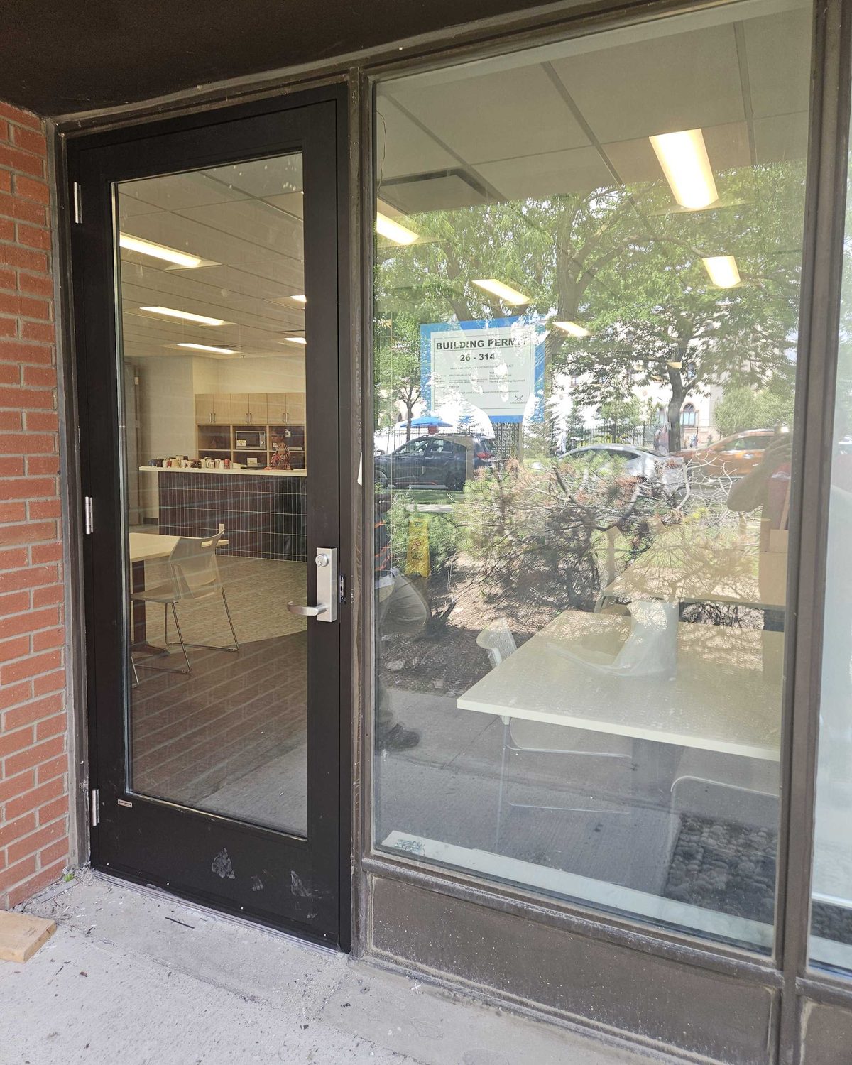 The old aluminum storefront entrance door at a Mississauga laboratory before replacement, its bottom rail blistered and chipped back to bare metal