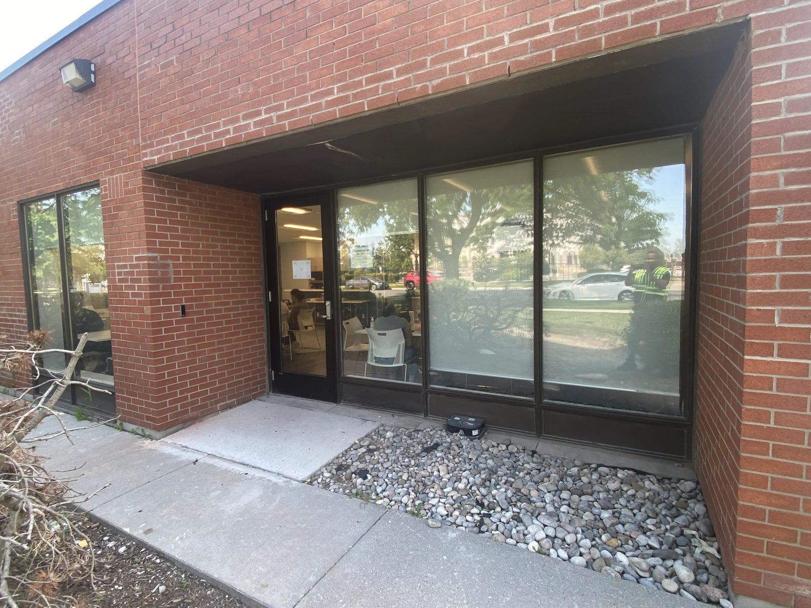 A new dark aluminum storefront entrance door and frame set into the brick recess of a Mississauga laboratory building, with the glazed elevation running off to the right, installed by Canuck Door Systems