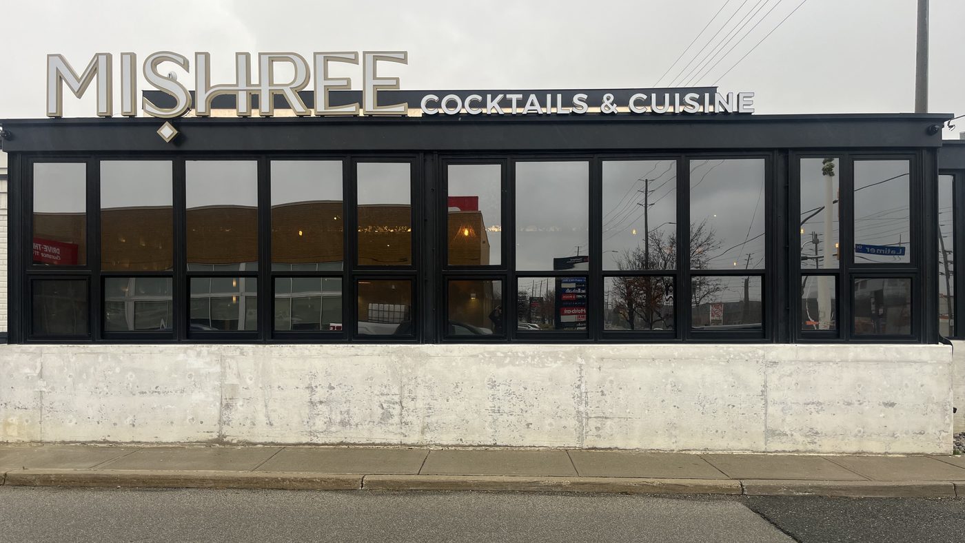 The Mishree restaurant in Mississauga by day, a long run of dark-framed glazing under the MISHREE cocktails and cuisine sign, above a white base wall
