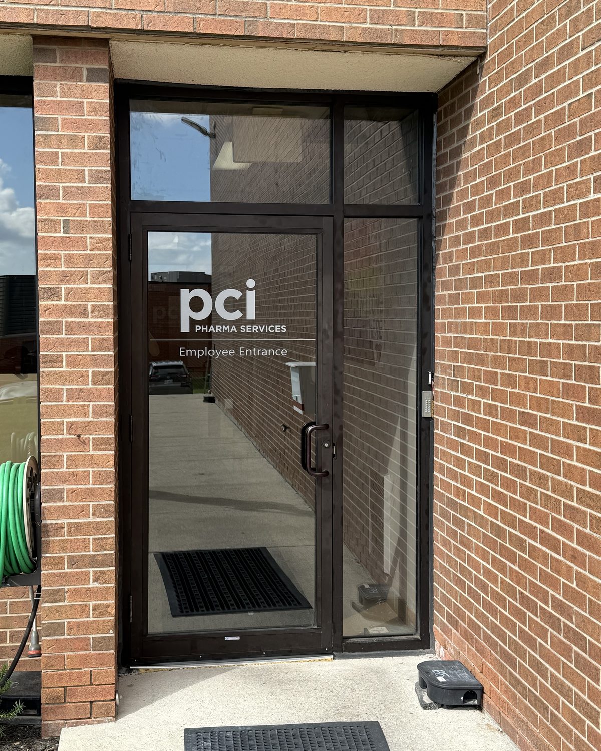 The new aluminum storefront door and sidelite at PCI Pharma Services in Mississauga, set into brick, with the company logo on the glass