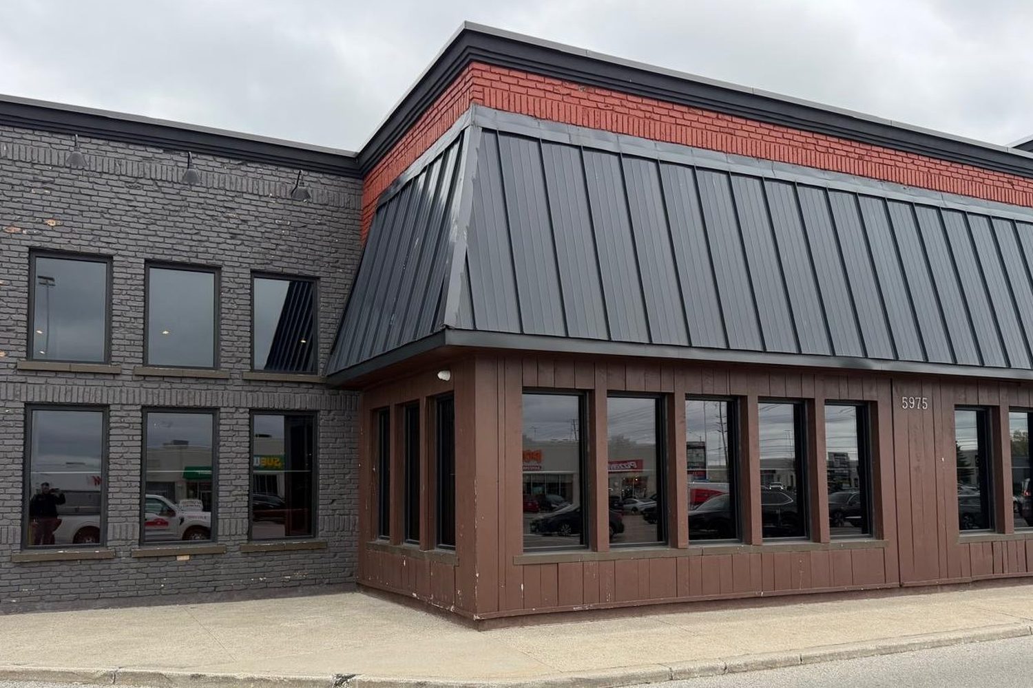 The corner of the Tandoori Flame restaurant building in Mississauga with new aluminum windows on the ground and upper floors, under a dark standing-seam metal roof